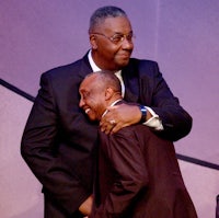 a man in a suit hugging another man