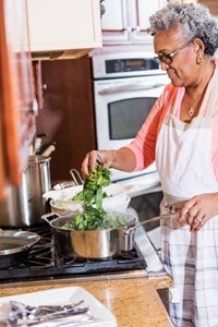 an older woman preparing food in the kitchen