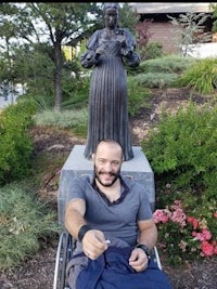 a man in a wheelchair in front of a statue